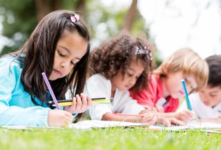 Happy group of children coloring at the park